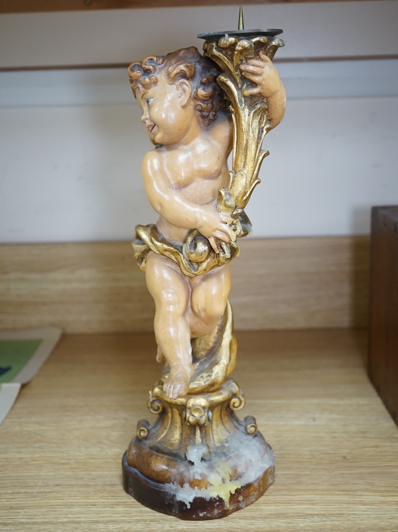 An Austrian carved and partially gilt cherub pricket candlestick, 37cm high. Condition - fair to good